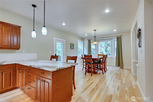 kitchen with a peninsula, light wood finished floors, and brown cabinets