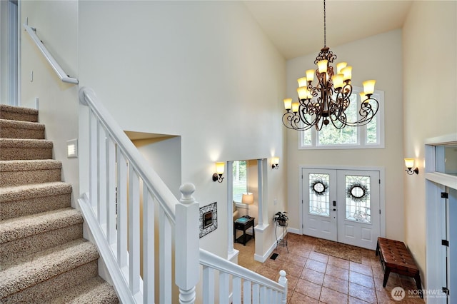 foyer with stairs, a chandelier, a high ceiling, light tile patterned floors, and baseboards
