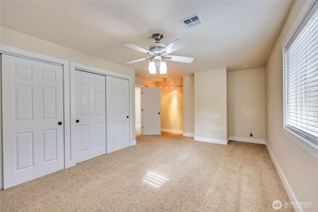 unfurnished bedroom featuring a closet, visible vents, baseboards, ceiling fan, and light colored carpet