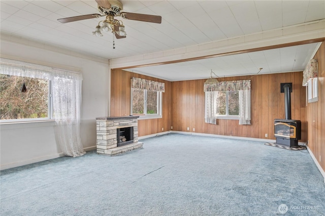 77 S Welcome Slough, Cathlamet, WA 98612 - unfurnished living room featuring wood walls, a wood stove, carpet floors, a ceiling fan, and a stone fireplace