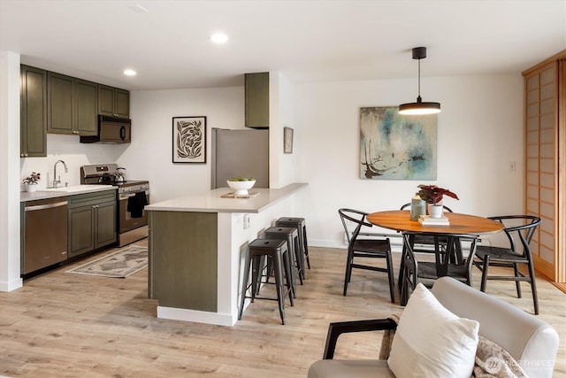 2501 Canterbury Ln E Unit 122, Seattle, WA 98112 - kitchen featuring light wood-style floors, light countertops, stainless steel appliances, and a kitchen breakfast bar
