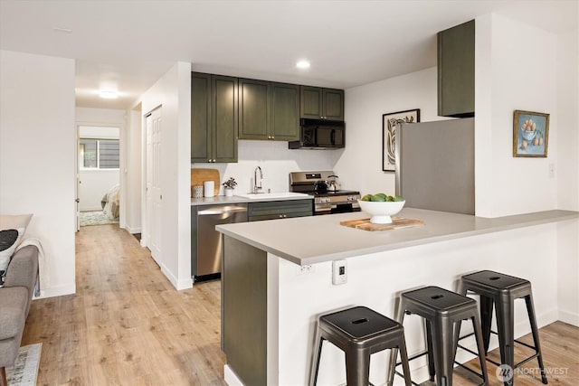 2501 Canterbury Ln E Unit 122, Seattle, WA 98112 - kitchen featuring light countertops, a kitchen bar, stainless steel appliances, light wood-style flooring, and a peninsula