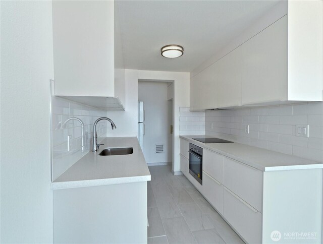 1156 Alki Ave SW Unit 204, Seattle, WA 98116 - kitchen featuring light countertops, modern cabinets, a sink, black appliances, and backsplash