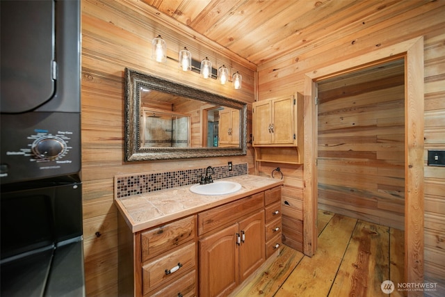 9381 Olalla Cayon Rd, Cashmere, WA 98813 - bathroom with stacked washer / drying machine, vanity, wooden walls, wooden ceiling, and wood-type flooring