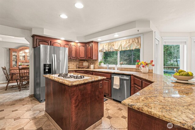 11312 134th Avenue Ct E, Puyallup, WA 98374 - kitchen with a kitchen island, light stone counters, a sink, stainless steel appliances, and backsplash