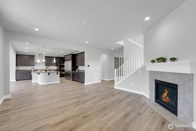 19504 141st Street Ct E, Bonney Lake, WA 98391 - unfurnished living room featuring stairway, light wood finished floors, a tile fireplace, baseboards, and recessed lighting
