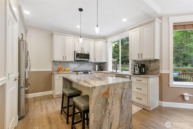 kitchen with baseboards, light stone counters, a sink, light wood finished floors, and appliances with stainless steel finishes