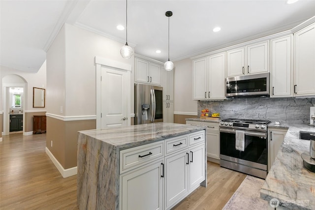 kitchen with a kitchen island, crown molding, arched walkways, tasteful backsplash, and stainless steel appliances
