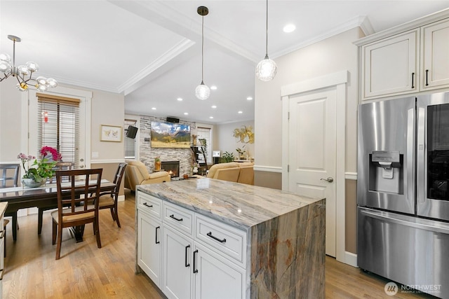 kitchen featuring stainless steel fridge, light wood-style floors, ornamental molding, and a fireplace