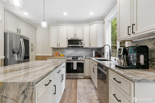 kitchen with tasteful backsplash, light stone counters, a sink, appliances with stainless steel finishes, and hanging light fixtures