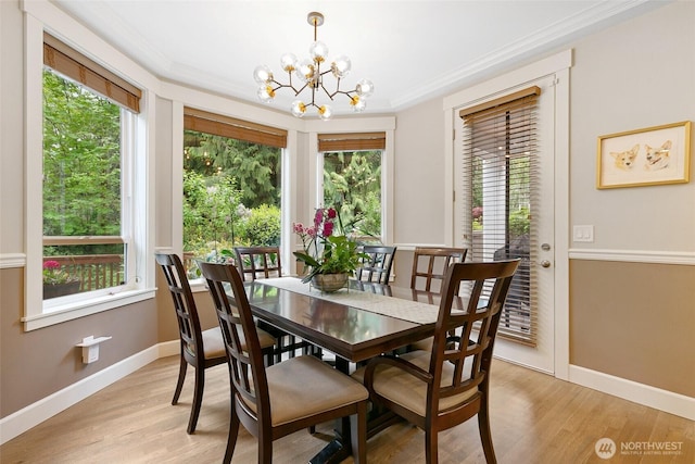 dining room featuring baseboards, an inviting chandelier, ornamental molding, and light wood-type flooring