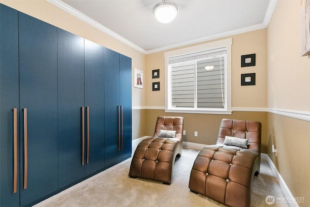 sitting room with carpet floors, crown molding, and baseboards