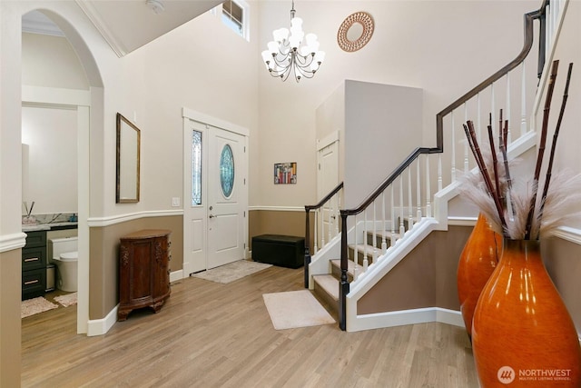 entrance foyer with stairway, arched walkways, wood finished floors, and visible vents