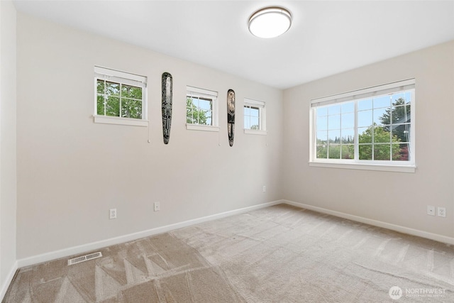 unfurnished room with baseboards, visible vents, and carpet