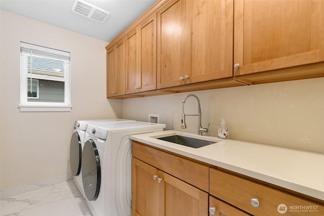 washroom with visible vents, cabinet space, a sink, marble finish floor, and washer and clothes dryer