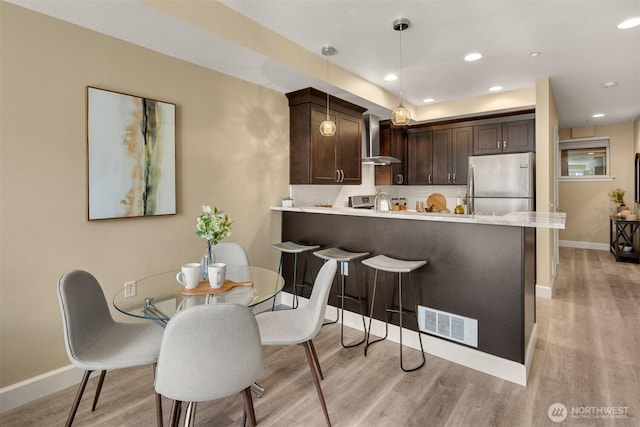 10047 Main St Unit 305, Bellevue, WA 98004 - kitchen featuring stainless steel fridge, wall chimney range hood, light wood-type flooring, dark brown cabinetry, and recessed lighting