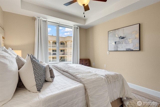 10047 Main St Unit 305, Bellevue, WA 98004 - bedroom featuring wood finished floors, baseboards, a tray ceiling, and ceiling fan