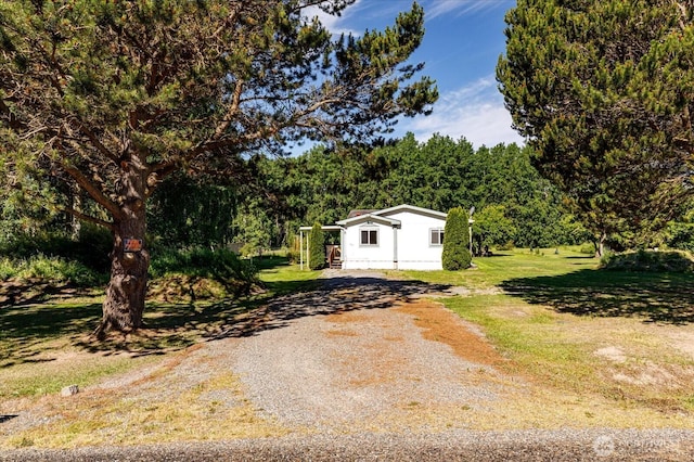exterior space with a wooded view, a front lawn, and gravel driveway