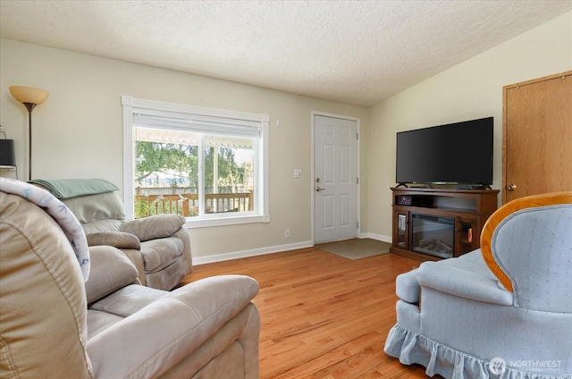 living area with baseboards, a textured ceiling, and wood finished floors