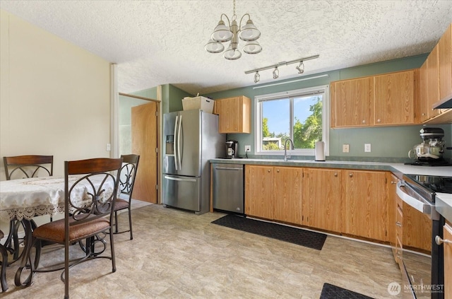 kitchen with stainless steel appliances, a textured ceiling, an inviting chandelier, and light floors