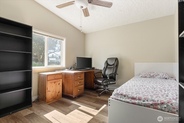 bedroom with a textured ceiling, a ceiling fan, wood finished floors, and lofted ceiling