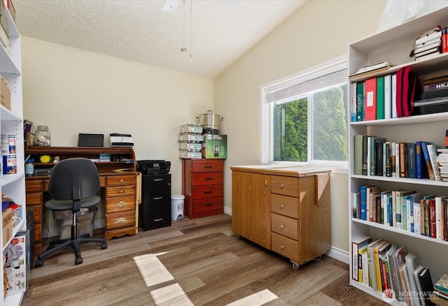 office space featuring light wood-type flooring, baseboards, and vaulted ceiling