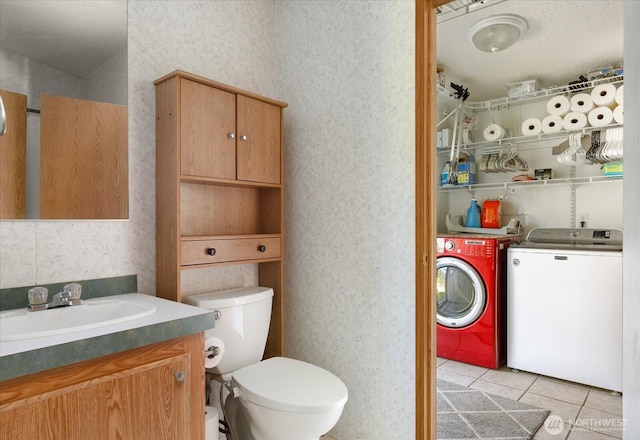 bathroom with toilet, wallpapered walls, washing machine and dryer, and tile patterned floors