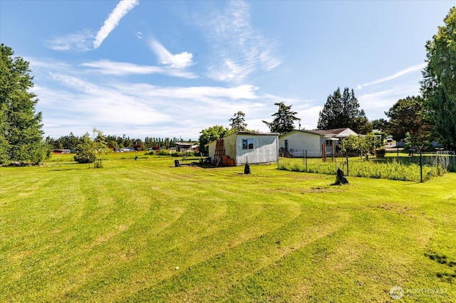 view of yard with fence, an outbuilding, and a shed