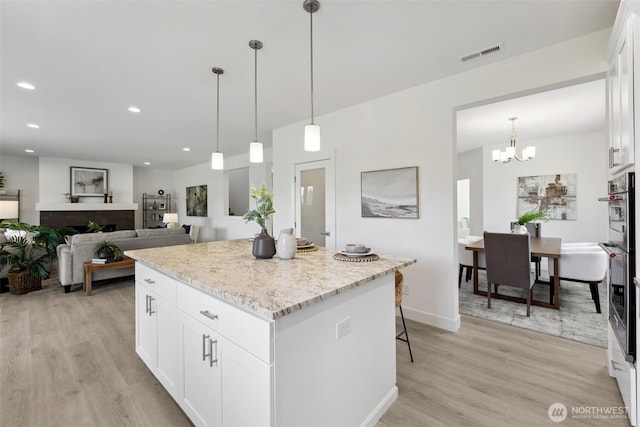 5842 229th Ave E, Buckley, WA 98321 - kitchen featuring light wood-type flooring, a kitchen island, a chandelier, white cabinets, and recessed lighting