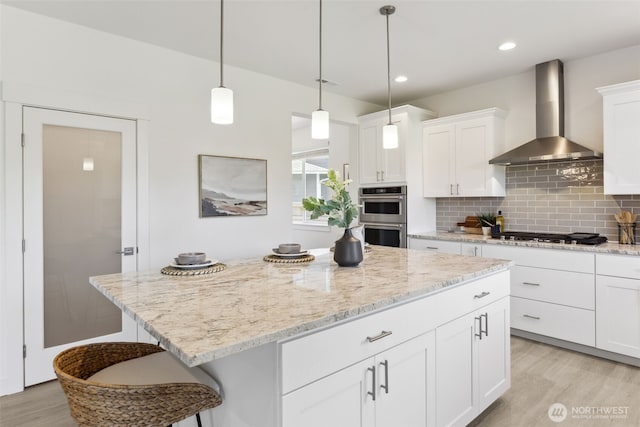 5842 229th Ave E, Buckley, WA 98321 - kitchen featuring wall chimney exhaust hood, appliances with stainless steel finishes, light wood-style flooring, backsplash, and a center island