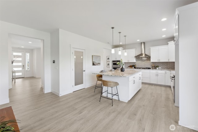 5842 229th Ave E, Buckley, WA 98321 - kitchen featuring wall chimney range hood, a kitchen island, double oven, light wood-type flooring, and recessed lighting