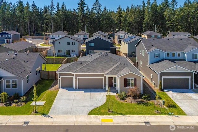 view of front facade featuring concrete driveway, fence, a residential view, and a garage
