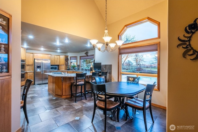 dining room with a notable chandelier, high vaulted ceiling, and baseboards