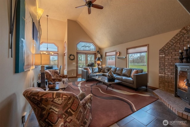 living room featuring ceiling fan with notable chandelier, high vaulted ceiling, baseboards, and a textured ceiling