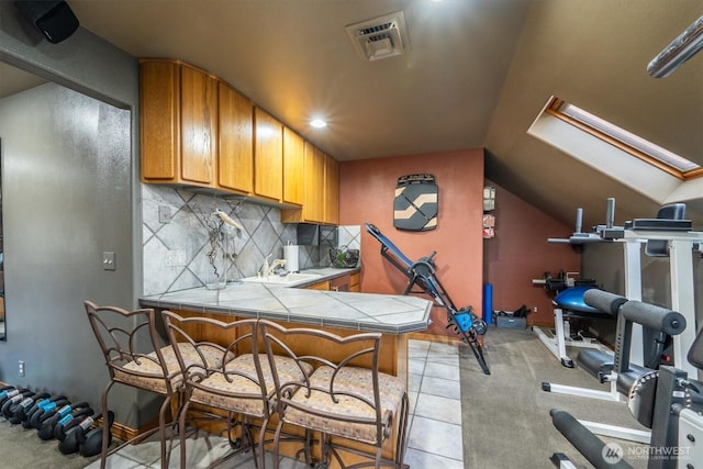 workout area featuring visible vents, light tile patterned floors, and vaulted ceiling with skylight