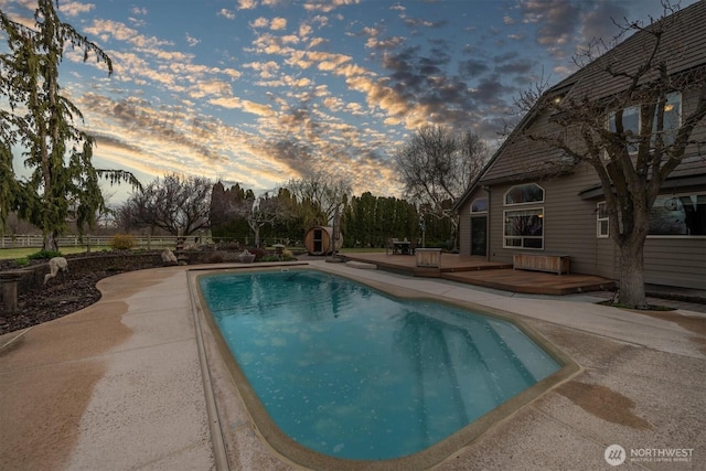 pool with a patio area, a wooden deck, and fence
