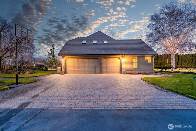 view of front facade with a garage, a yard, and decorative driveway