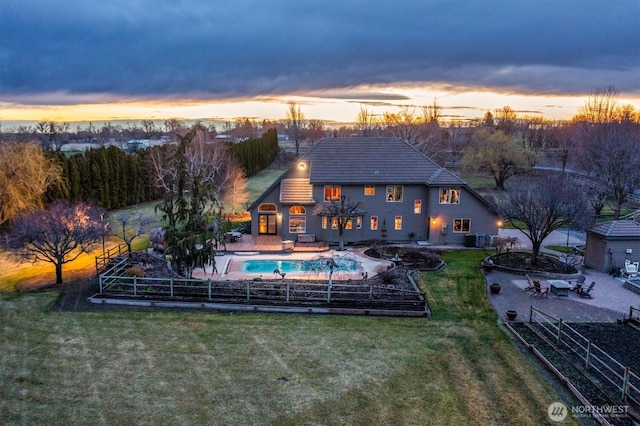 rear view of house featuring a tile roof, fence, a patio, a fenced in pool, and a lawn