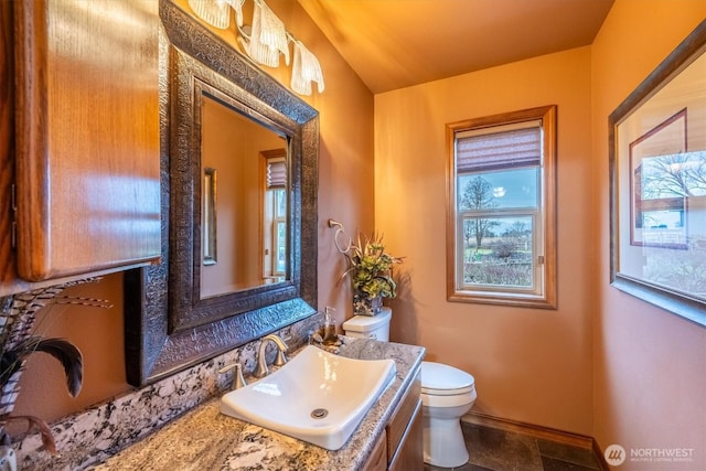 half bathroom featuring baseboards, toilet, and vanity