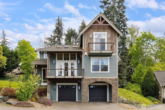 view of front of home with an attached garage, aphalt driveway, stone siding, and a balcony