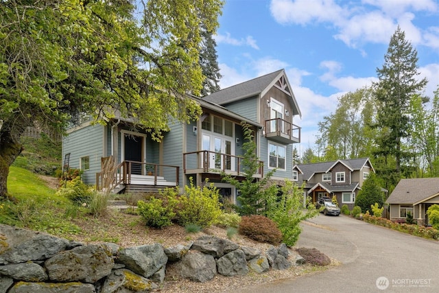 view of front of home with driveway and a balcony