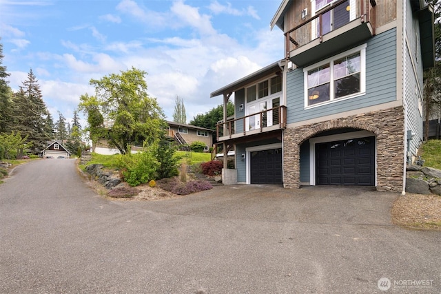 view of front facade featuring aphalt driveway, a garage, and stone siding