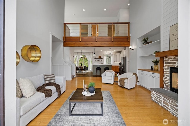 living area featuring a fireplace, a towering ceiling, and light wood-type flooring