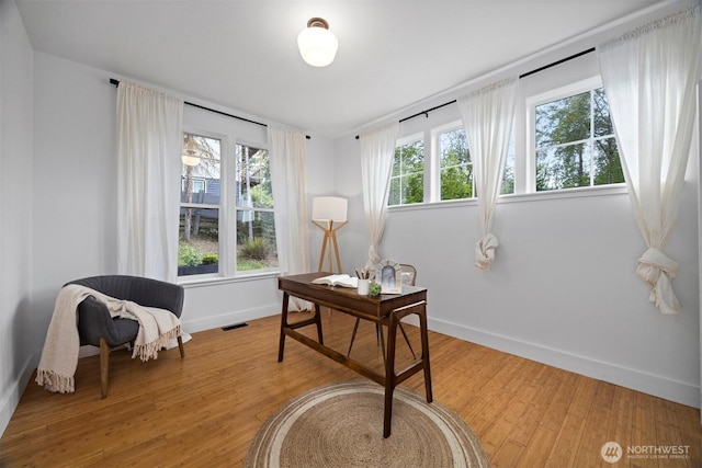 office space with baseboards, light wood-style flooring, and visible vents