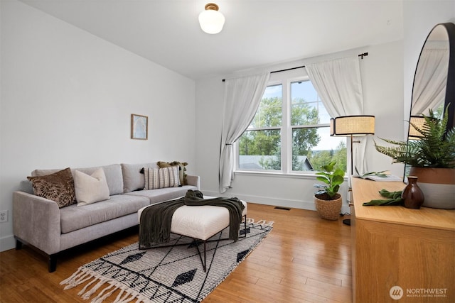 living room with baseboards, visible vents, and wood finished floors