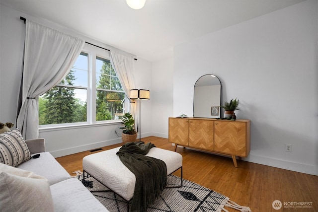 sitting room with baseboards, visible vents, and wood finished floors