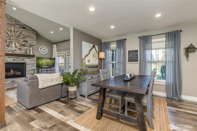 16005 SE Lake Holm Rd, Auburn, WA 98092 - dining space featuring wood finished floors, a stone fireplace, vaulted ceiling, and a wealth of natural light