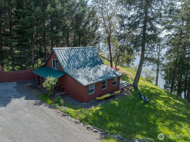 view of side of property with fence, a yard, and metal roof