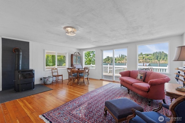 275 State Route 409, Cathlamet, WA 98612 - living room featuring a wood stove, a textured ceiling, wood-type flooring, baseboards, and a water view