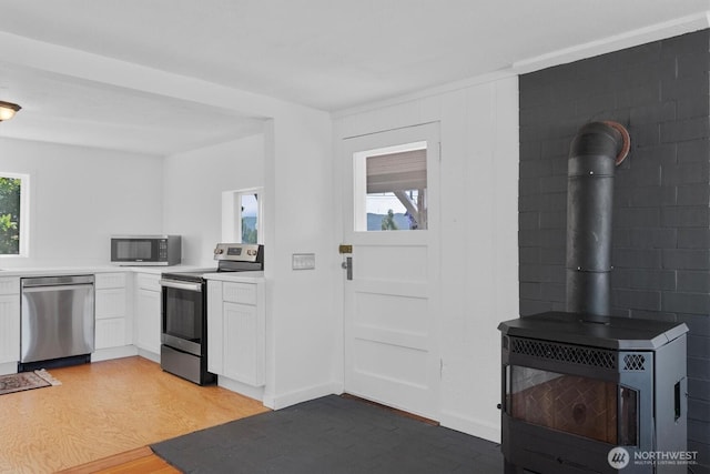 275 State Route 409, Cathlamet, WA 98612 - kitchen featuring light countertops, a wood stove, light wood-type flooring, white cabinets, and appliances with stainless steel finishes